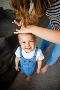 Mother makes her little daughter's hair. Hair care from an early age. Stock Photos