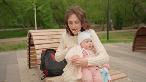 Mother Manages Tasks, Mother Multitasks With Child In Park Setting, Mother Stock Footage 324188995
