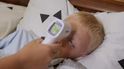 A mother measures the temperature of a sick boy with an infrared thermometer. Stock Footage 161222110