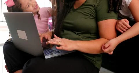Mother multi-tasking, using computer laptop at home while parenting two child Foto stock