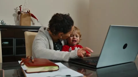 Mother multitasking with child at home working on laptop Stock Footage 296551551