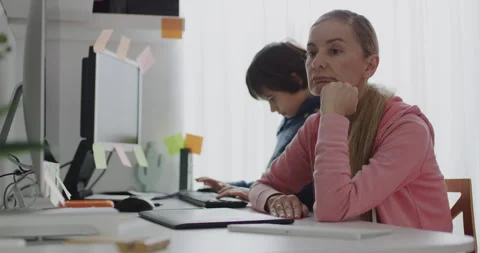 Mother multitasking remote work while bored child sits nearby Stock Footage 275581311
