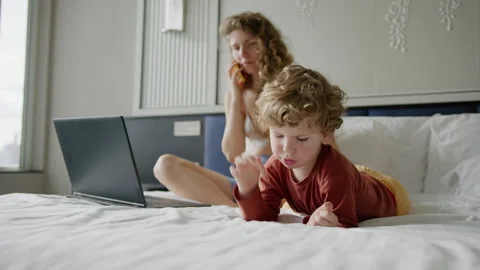 Mother multitasking while working on a laptop with her child playing games on Stock Footage 296513656