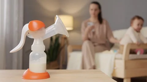 A mother multitasks by using a breast pump in a relaxed living room while 库存影片 301247170