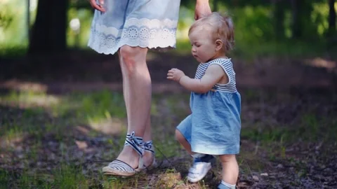 Mother with a one-year-old child walks through the woods or park. first steps Stock Footage 132662913