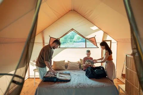 Mother passing stack of clothes to her teenage son Stock Photos