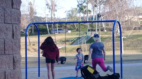 Mother picks up spin spin in circle her son play on swing slow motion Video stock 124950692