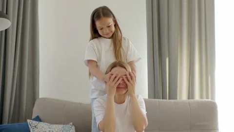 Mother piggybacks her little cute daughter seated on couch. Stock Footage 252546292