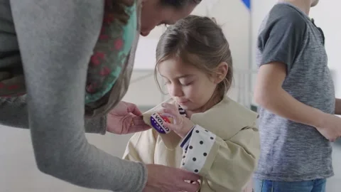Mother pinning voting button on daughter in American polling place Stock Footage 220973692