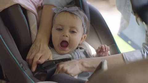 Mother Places Her Baby Girl In Car Seat, Puts Arm Through Strap Stock Footage