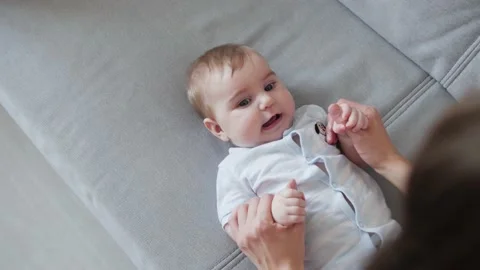 Mother playing and having fun with her baby daughter lying on the bed at home. Stock Footage 131990550