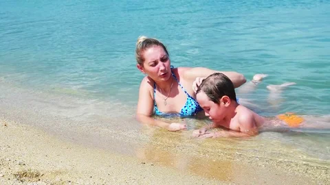 Mother playing with her young son in water Stock Footage 78998615