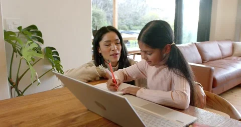 Mother pointing to notebook while daughter writing under guidance with pencil Stock Footage 344219799