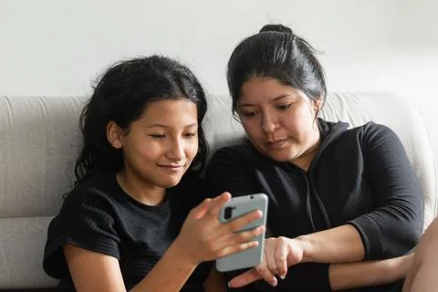 Mother pointing at the phone screen while spending quality time with her da.. Stock Photos