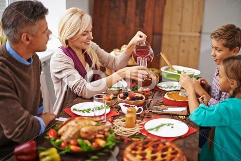 Mother pouring fruit drink to her children at thanksgiving dinner Stock Photos