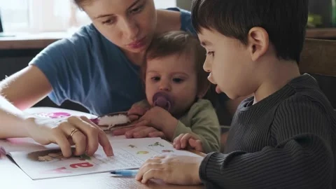 Mother practicing reading with her boy, sitting in front of a kitchen table Stock Footage 190595488