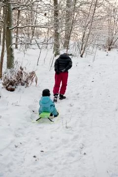Mother pulling snow sledge up a hillside Stock Photos