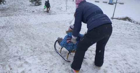 Mother Pushes Little Son on Sledge Little Boy Rides on a Sledge Downhill and Stock Footage 59041290