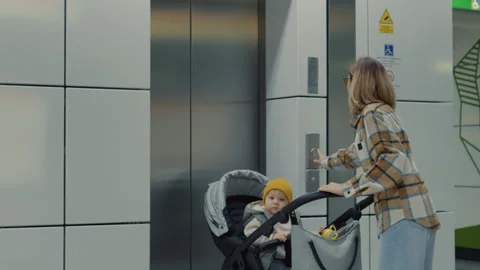 Mother pushing stroller entering elevator Stock Footage 302472639