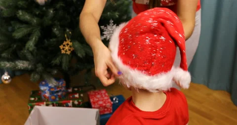 Mother puts her son on the head with a new year hat for Santa Claus Stock Footage 98911084