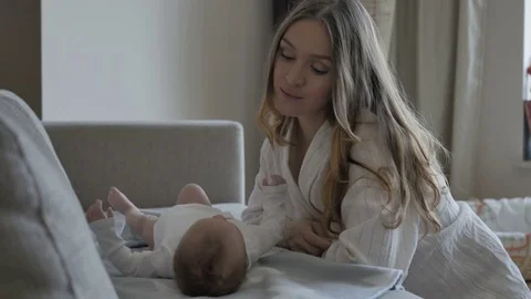 Mother putting baby on sofa 库存影片 80459629