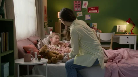 Mother Putting Mug on Side Table and Putting Hand to Forehead of Sick Sleepy Kid Stock Footage 335471923