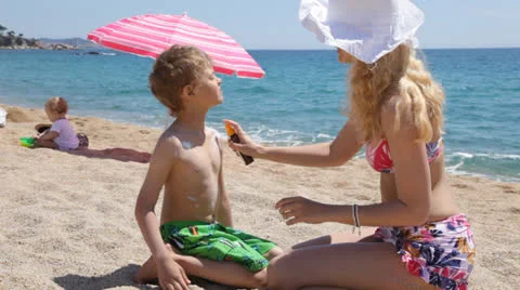 Mother putting sunscreen on her son Stock Footage 24804531