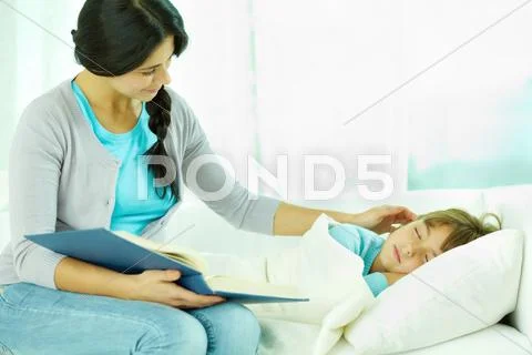 Mother reading a book while her daughter sleeping Stock Photos