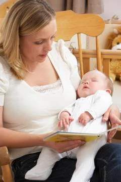 Mother Reading Story To Baby In Nursery Stock Photos