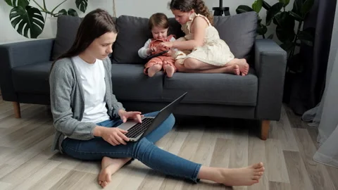 Mother remote working online using laptop, two daughters holding smartphone Stock Footage 200913691