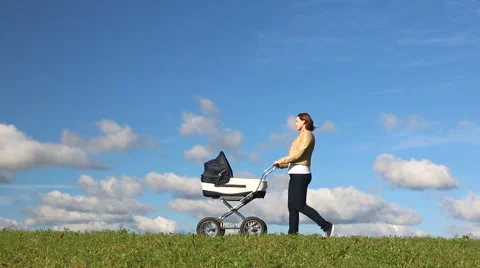 Mother running while pushing a stroller on meadow Stock Footage 67560871