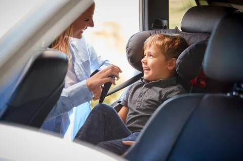 Mother Securing Son Into Rear Child Seat Before Car Journey Stock Photos