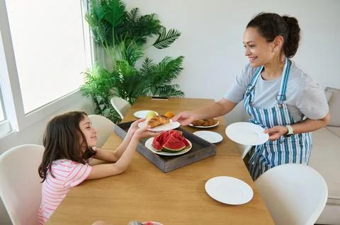 Mother Serving Homemade Breakfast to Child at Bright Kitchen Table Stock-Fotos