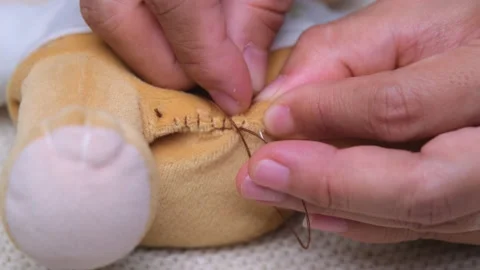 Mother sews up a torn doll for her little daughter by hand. Vidéo 201281318