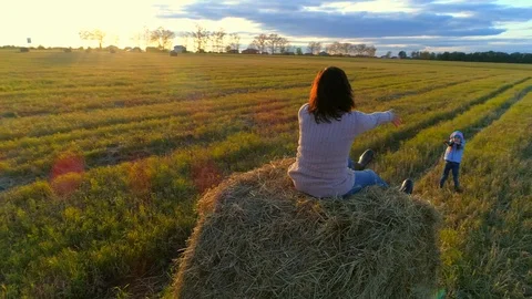Mother sit on the straw stack and takes for hands her daughter on the rustic Stock Footage 85667501