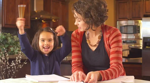 A mother sits at the kitchen table and helps her young daughter do her homework Stock-Footage 34003450