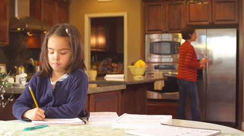 A mother sits at the kitchen table and helps her young daughter do her homework Video stock 34003469