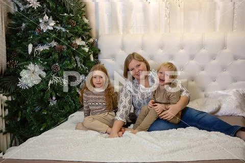 Mother is sitting on the bed. children are sitting nearby. hugging smile Stock Photos