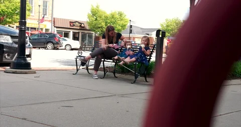 Mother sitting on a bench with her two girls eating ice cream in America Stock Footage 109560056