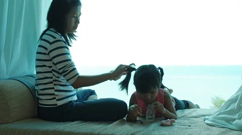 Mother sitting at sofa and combed her daughter 's hair. Stock Footage 62175258