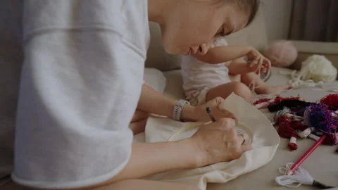 Mother sitting on the sofa next to her child sketching with a pen on the canvas Stock Footage 255526480