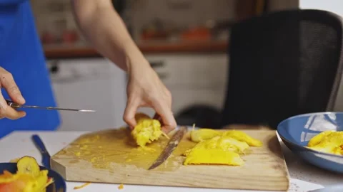 Mother slicing ripe mango for son in the kitchen Stock Footage 319420600