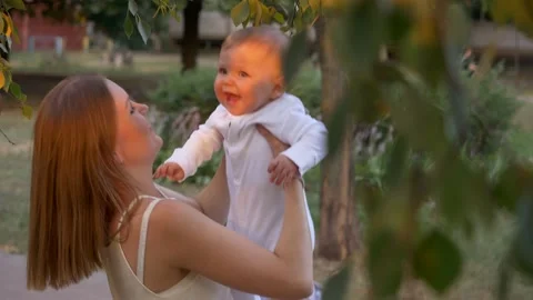 Mother with a small child plays fun outdoors. Around the trees. Stock Footage 130705310
