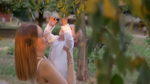 Mother with a small child plays fun outdoors. Around the trees. Stock Footage 130706044