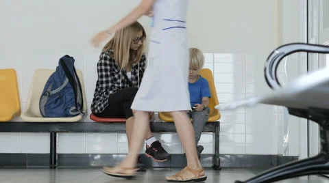 Mother with son sitting in queue to doctor in clinic playing game on phone. Stock Footage 61876247