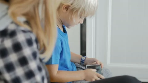 Mother with son sitting in queue to doctor in clinic playing game on phone. Stock Footage 61877000