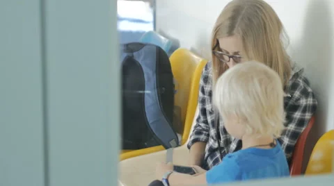 Mother with son sitting in queue to doctor in clinic playing game on phone. Stock Footage 61877318