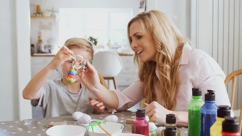 Mother With Son Sitting At Table Decorating Eggs For Easter At Home Stock Footage 114308371