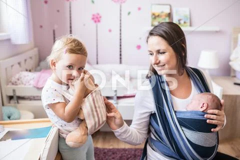 Mother with son in sling and daughter carrying teddy bear Stock Photos