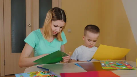Mother spending time with son, making application, child cutting colored paper Stock Footage 187171033